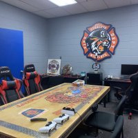 A recreation room for downtime between calls, with gaming chairs, a puzzle table, and the department emblem on the wall.